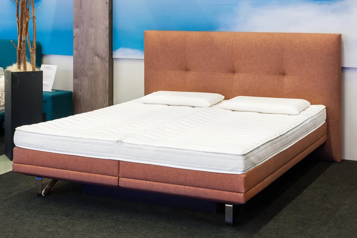 Wasserbett mit braunem Polsterrahmen und weißer Liegefläche